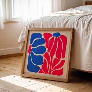 May include: A framed print of an abstract floral design with blue and red shapes on a white background.