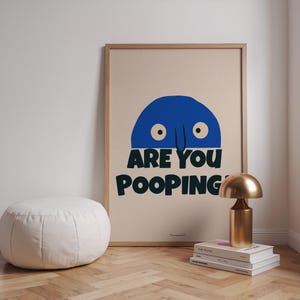 Op de afbeelding: Een beige poster met een blauw cartoonfiguur met twee ogen en een neus. Het figuur kijkt over de tekst "Are you pooping?" in zwarte letters.