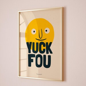 K&ouml;nnte beinhalten: Ein gerahmter Druck mit einem gelben Smiley-Gesicht und dem Text "YUCK FOU" in Schwarz. Der Druck ist auf einem beigefarbenen Hintergrund und hat einen goldenen Rahmen.