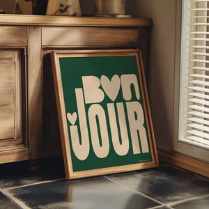 May include: A green framed poster with white text that says "Bon Jour" with a heart shape in the "o" of "Bon".