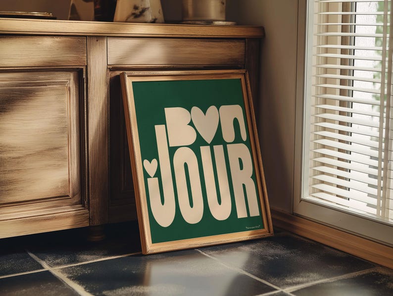 May include: A green framed poster with white text that says "Bon Jour" with a heart shape in the "o" of "Bon".
