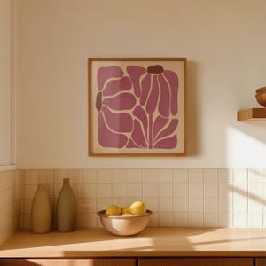 Pu&ograve; includere: Una stampa incorniciata di un design floreale astratto rosa con una cornice in legno. La stampa &egrave; appesa a una parete piastrellata bianca sopra un bancone in legno.