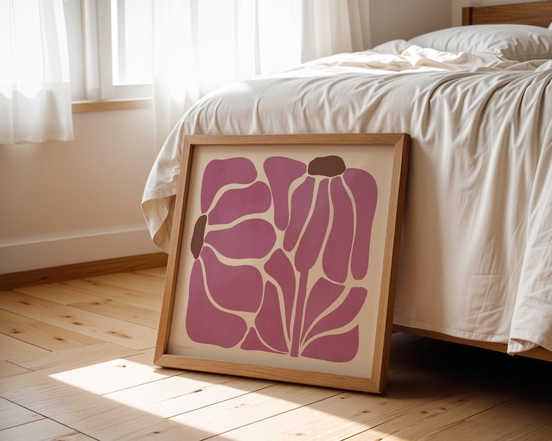 Pu&ograve; includere: Una stampa incorniciata di un design floreale astratto rosa con accenti marroni. La stampa &egrave; in una cornice di legno chiaro e si trova su un pavimento di legno.
