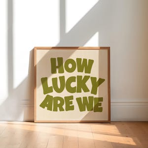 May include: A framed print with a beige background and green text that reads "HOW LUCKY ARE WE".
