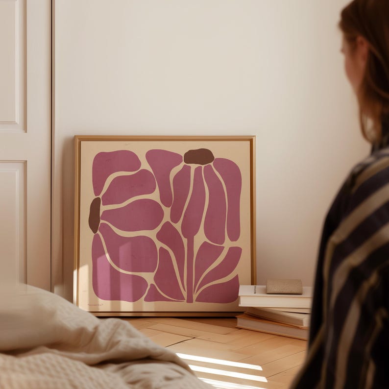 Pu&ograve; includere: Una stampa incorniciata di un design floreale astratto rosa su sfondo crema. Il fiore &egrave; composto da diverse forme sovrapposte.