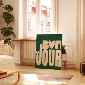 May include: A green and cream colored wall art print with the text "Bonjour" in a stylized font. The text is in a cream color and the background is a deep green.