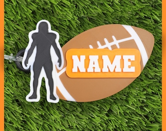 May include: A football-themed luggage tag with a brown football shape and white stripes. An orange rectangle with the word "NAME" in white is centered on the football. A black and white football player silhouette is attached.