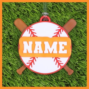 May include: A baseball-themed ornament with a white baseball design, red stitching, and two brown bats crossed behind it. The ornament features the word "NAME" in white letters on an orange background.