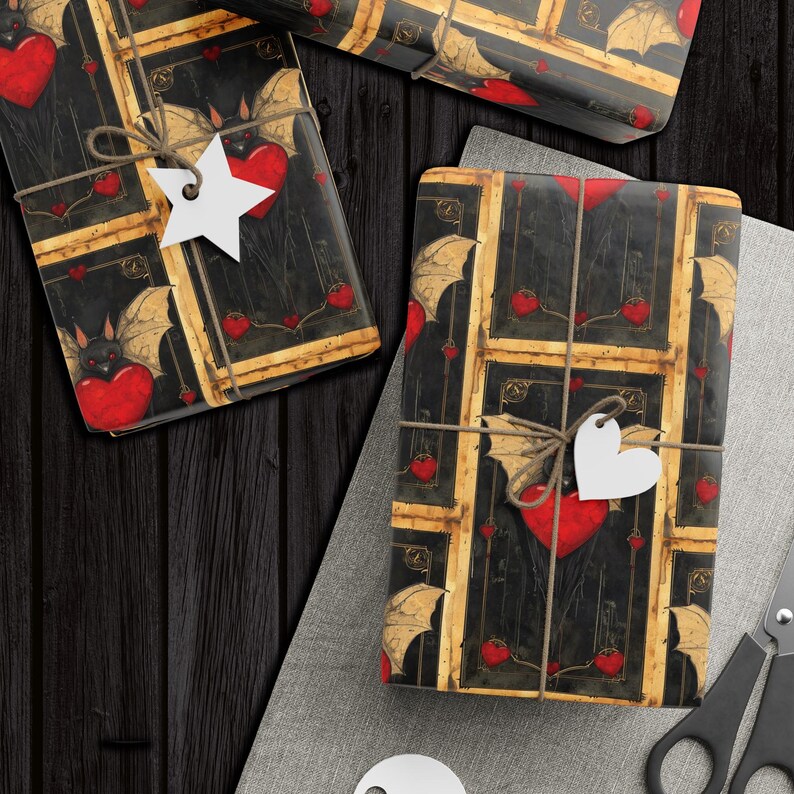Pode incluir: Duas caixas de presente embrulhadas em papel estampado em preto e dourado com cora&ccedil;&otilde;es vermelhos e morcegos. O papel tem um visual e uma sensa&ccedil;&atilde;o vintage. As caixas s&atilde;o amarradas com barbante e decoradas com estrelas e cora&ccedil;&otilde;es de papel branco.