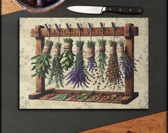 Pode incluir: Uma impressão decorativa com tema de cozinha com um suporte de madeira com várias ervas secas penduradas em pregadores. A impressão inclui o texto "Kitchen Vibes" e uma faca. As ervas são em tons de verde, roxo e castanho.