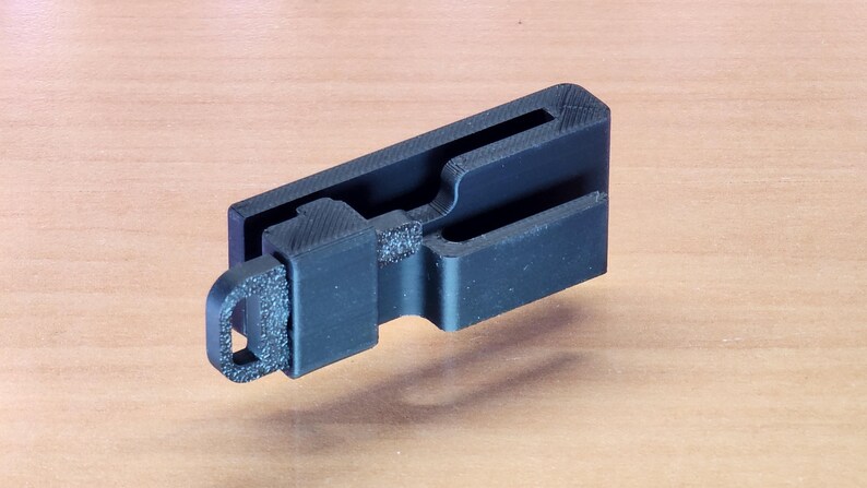 May include: A black plastic key holder with a loop for attaching to a keychain. The holder has a slot for holding a key.