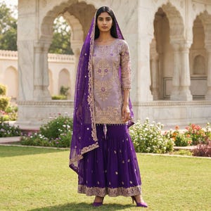 May include: A lavender tunic featuring intricate gold embroidery paired with deep purple wide-leg trousers and a matching sheer purple dupatta with gold border detailing. The ensemble includes long sleeves and a coordinated color palette throughout.