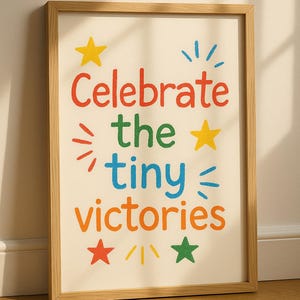 May include: A framed print with the text "Celebrate the tiny victories" in colorful letters. The print features stars and other decorative elements.