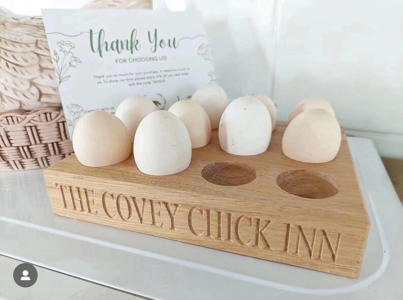 May include: Wooden egg holder with the text "The Covey Chick Inn" engraved on the front. The holder has six slots and is filled with six white eggs.