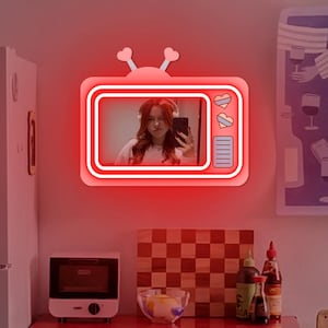 May include: Red neon sign shaped like a vintage television with a woman's face in the screen. The sign has white outlines and two small hearts on the top.