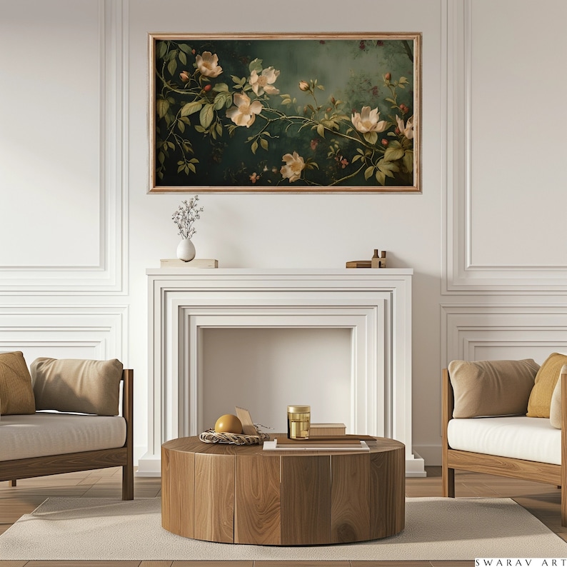 May include: A framed painting of white flowers with green leaves on a dark green background. The painting is hanging above a white fireplace mantel with a wooden coffee table in front of it.