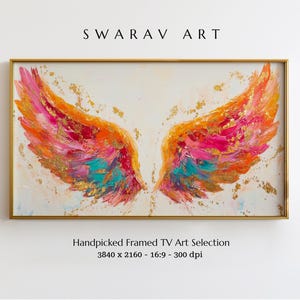 May include: Framed artwork featuring abstract angel wings in vibrant colors of pink, orange, and teal, with gold accents. The artwork is displayed in a gold frame. The text "SWARAV ART" is at the top.