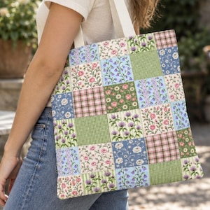 May include: A tote bag featuring a patchwork design of various floral patterns in shades of blue, green, pink, and white, combined with small green and white checkered squares. The bag has two white fabric shoulder straps and a rectangular shape.