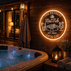 Könnte beinhalten: Ein Neon-Schild mit der Aufschrift "The Retreat Hot Tub" in einem kreisförmigen Design, mit dem Text "Est. 2024 Sip'n Dip". Das Schild befindet sich an einer Holzwand neben einem Whirlpool. Die Szene ist warm beleuchtet.