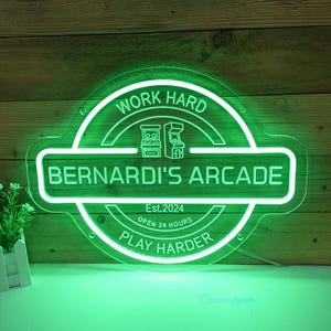 May include: Green neon sign with the text "Work Hard Play Harder" and "Bernardi's Arcade" with the arcade game icons and "Est. 2024 Open 24 Hours" in the center.
