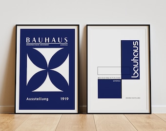 May include: Two framed posters with a Bauhaus theme. The left poster features a blue and white geometric design with the text "Bauhaus, Modernistische Bewegung, Ausstellung, 1919". The right poster features a blue rectangle with the text "bauhaus" and the text "Modernistische Ausstellung" in a smaller rectangle.
