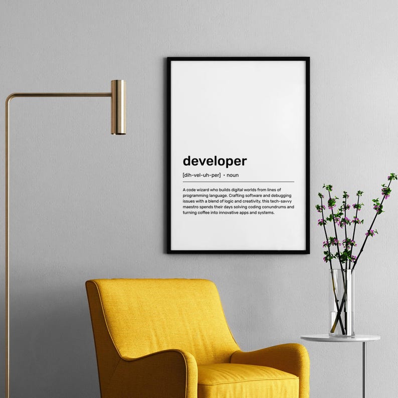 May include: A framed print with the word "developer" in a black frame. The definition of developer is written below the word. A yellow armchair and a gold lamp are in the foreground.