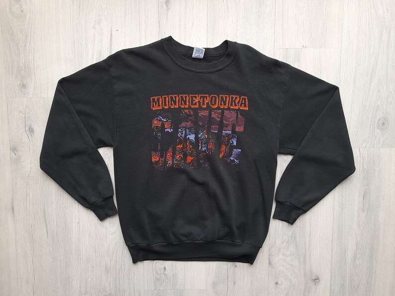 May include: Black sweatshirt with a graphic print of a sunset scene with the text "Minnetonka" and "Cabin Fever" in orange.