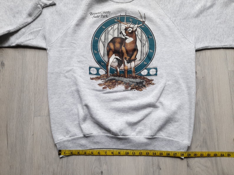 May include: Gray sweatshirt with a graphic print of a deer in a forest setting. The graphic includes the text "Brown County State Park".