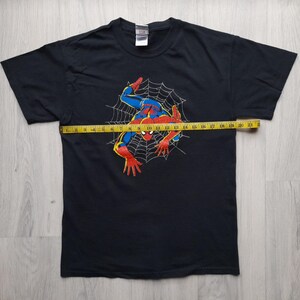 Pu&ograve; includere: T-shirt nero con grafica di Spider-Man in rosso, blu e giallo, su una ragnatela. Un metro a nastro giallo &egrave; posto sulla maglietta. Il design della maglietta &egrave; a tema supereroi.