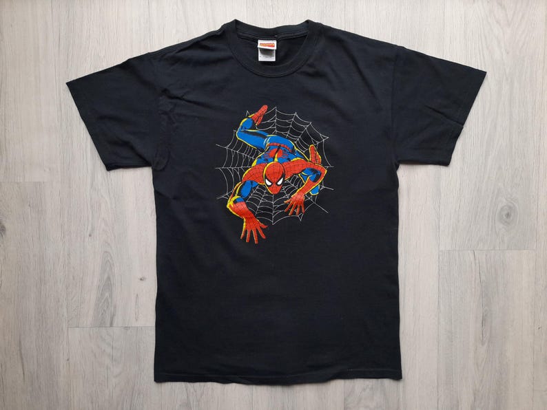 Pu&ograve; includere: T-shirt nero con grafica di Spider-Man. Il design mostra il supereroe nella sua tuta rossa e blu, con un contorno giallo, su una ragnatela bianca. La t-shirt &egrave; realizzata in materiale morbido.