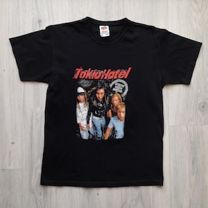 May include: Black t-shirt with the band Tokio Hotel printed in red. The shirt features a photo of the band members. The t-shirt is made of a soft material and has a crew neck.