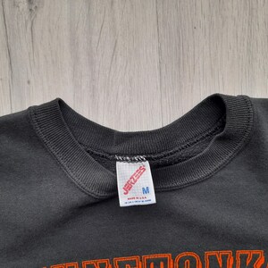 May include: Black sweatshirt with a Jerzees tag and the text "M" on it. The sweatshirt has a crew neck and is made of a soft, comfortable material.