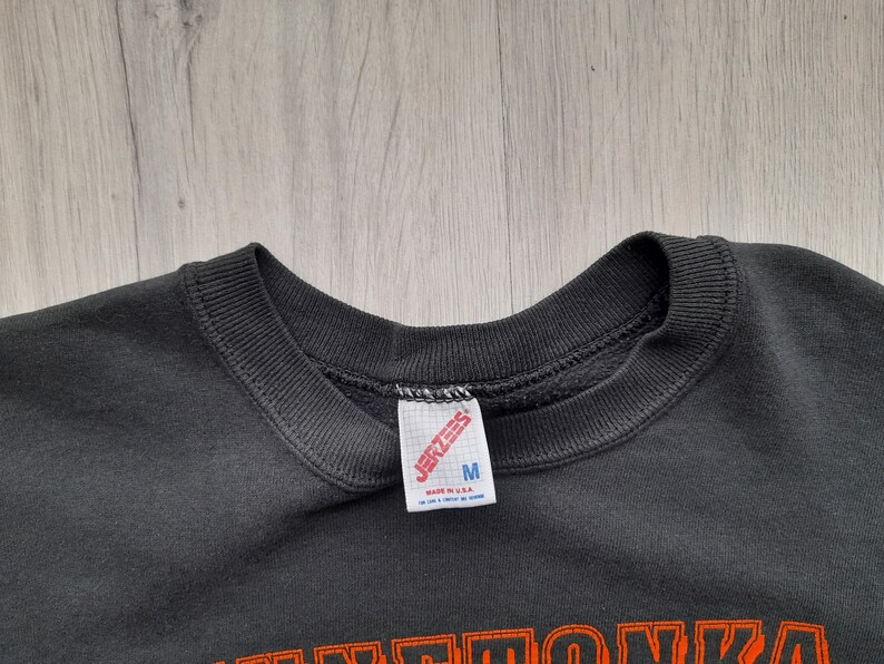 May include: Black sweatshirt with a Jerzees tag and the text "M" on it. The sweatshirt has a crew neck and is made of a soft, comfortable material.