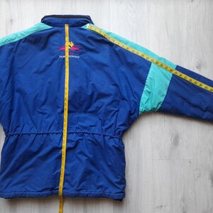 Puede incluir: Chaqueta vintage azul y turquesa con cintura con cord&oacute;n y logotipo en la espalda. La chaqueta se mide con una cinta m&eacute;trica amarilla. La chaqueta mide aproximadamente 76 cm de largo.