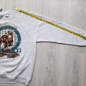 May include: Gray sweatshirt with a deer graphic and the text "Brown County State Park". The sweatshirt is laid flat with a measuring tape extending from the shoulder seam to the end of the sleeve, measuring 29 inches.