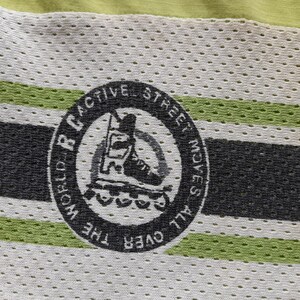 May include: A black and white logo on a green and white striped fabric. The logo says "RC World Active Street Moves All Over The" and features a silhouette of a person rollerblading.