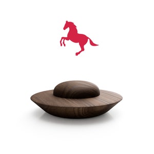 May include: A dark brown wooden saucer with a raised center, resembling a flying saucer. A red silhouette of a horse rearing up is above the saucer.