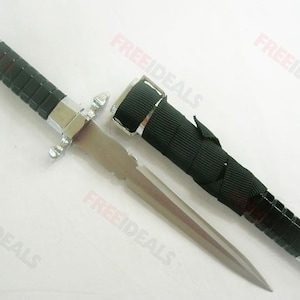 May include: A silver dagger with a black handle and a black nylon sheath. The sheath has a buckle and a strap.
