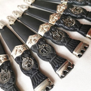 May include: A set of eight black and silver decorative knife handles with a woven pattern and a silver emblem.