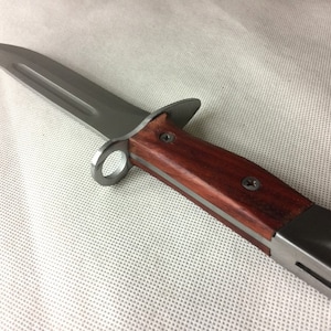 May include: A silver knife with a wooden handle. The handle is dark brown and has a silver ring near the blade.