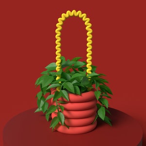 May include: A red, stacked planter filled with green foliage, featuring a yellow, coiled handle. The planter sits on a red plinth against a red backdrop. The handle's bright yellow provides a striking contrast.
