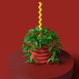May include: A red plant pot with a trailing green plant and a yellow zig-zag decoration. The pot is on a matching red stand against a red background. The plant has vibrant green leaves.