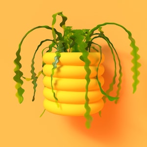 May include: A bright yellow, contemporary planter with a stacked, rounded design. It contains a green plant with long, wavy leaves. The background is a solid orange colour, providing a striking contrast.