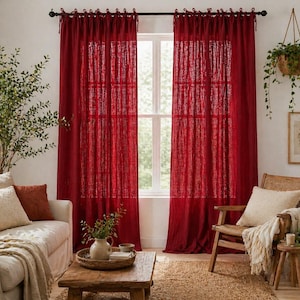 May include: Red linen curtains hanging in front of a window. The curtains are tied at the top with matching fabric. A sofa, coffee table, and chair are in front of the curtains.