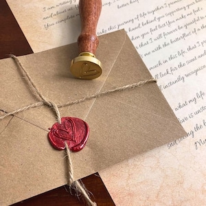 May include: A brown envelope with a red wax seal and a gold wax seal. The envelope is tied with twine. The envelope has a handwritten letter inside.