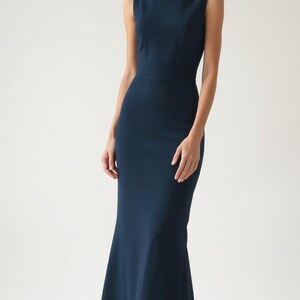 May include: A sleeveless, dark blue maxi dress with a bateau neckline and a fitted silhouette. The dress has a slight flare at the hem.