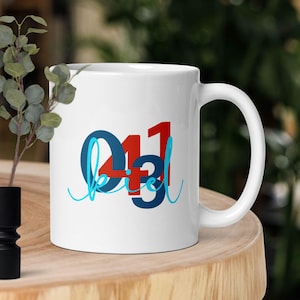 Könnte beinhalten: Weiße Keramiktasse mit einem blauen, roten und weißen Design, auf dem "041 kiel" steht.