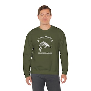 May include: Olive green sweatshirt with the text "ETHICAL ANGLING" above a fish graphic and the words "BLANKED AGAIN!" below. The graphic is white. The sweatshirt is a crew neck style.