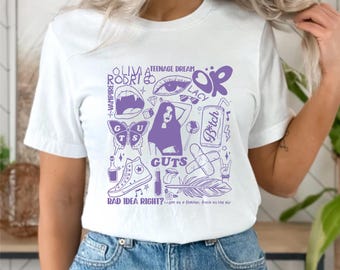 Puede incluir: Camiseta blanca con un diseño gráfico morado que presenta el texto "OLIVIA RODRIGO" y "GUTS". El diseño incluye ilustraciones de una mariposa, una zapatilla de caña alta y otros elementos. También está presente el texto "BAD IDEA RIGHT?"