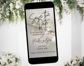 Può includere: Lo schermo di uno smartphone che mostra un annuncio di salvataggio della data per un matrimonio. L'annuncio presenta uno sfondo floreale con due anelli dorati e il testo "Save the Date", "Si prega di salvare la data per la celebrazione del matrimonio di Maddie & Tyler", "Sabato 18 giugno 2026" e "Invito formale a seguire".